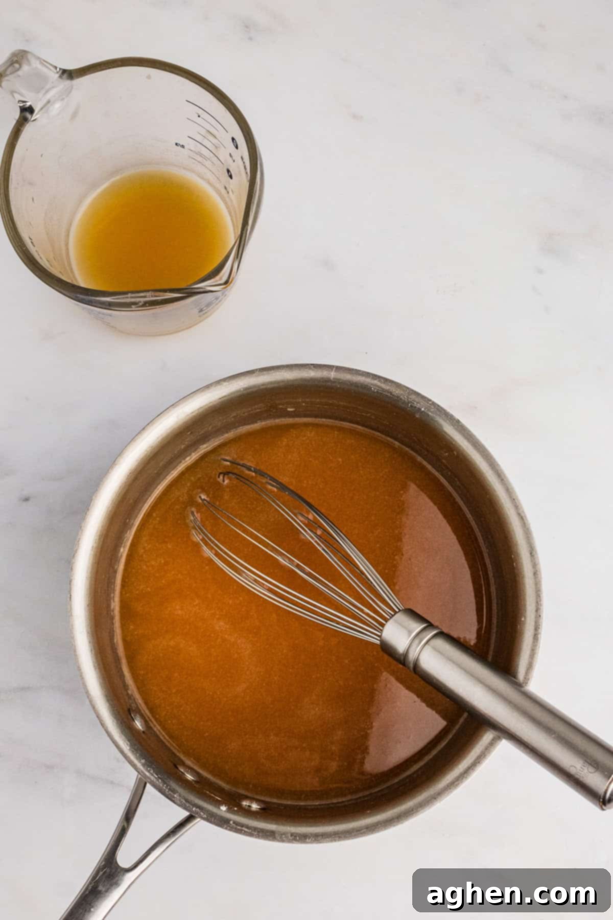 A saucepan filled with turkey gravy, with a wire whisk actively stirring the mixture to ensure smoothness and even thickening.