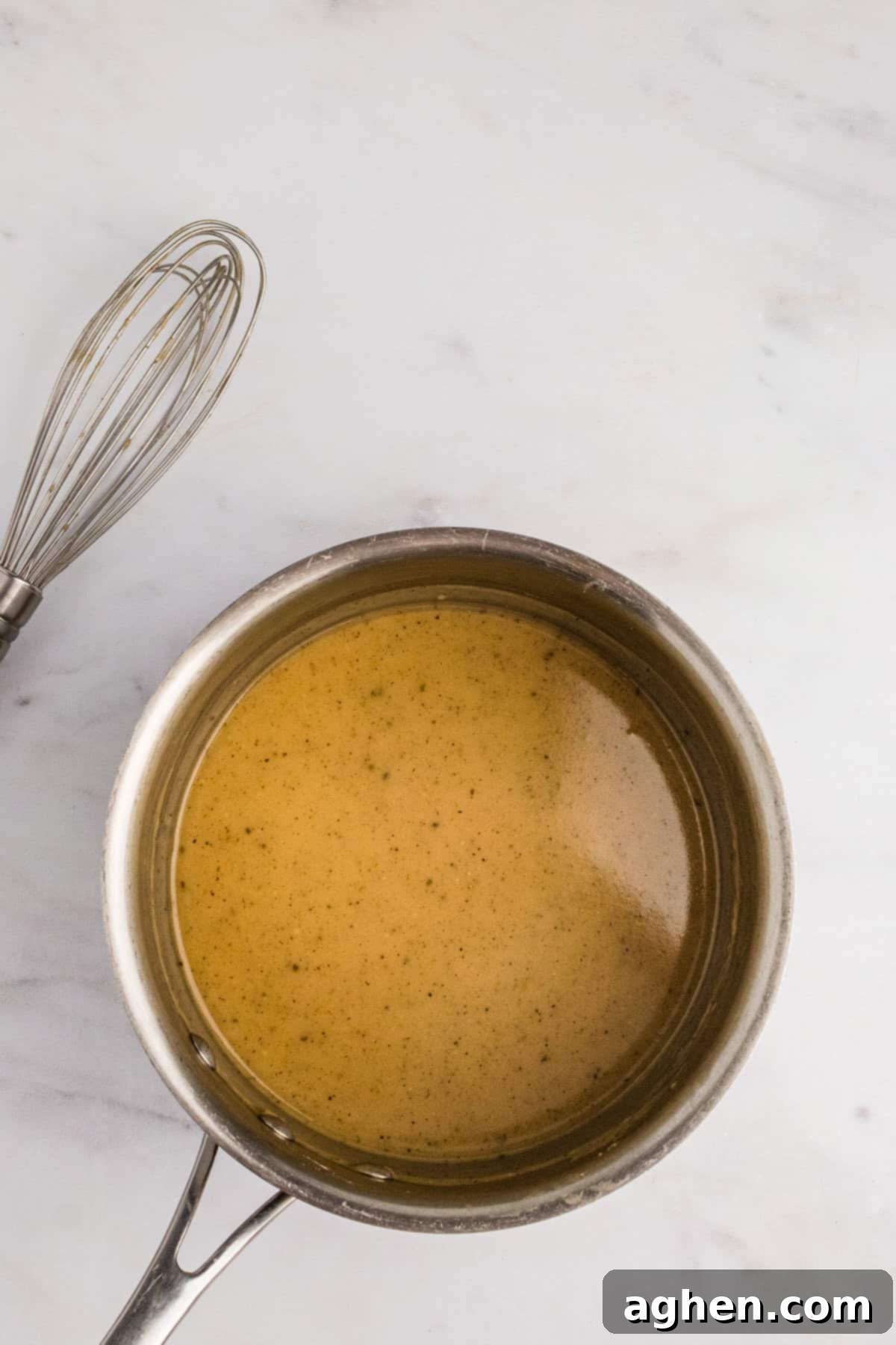 Easy-Homemade-turkey-gravy-recipe - A pot of homemade turkey gravy simmering on the stovetop, visibly thickening to a rich consistency.