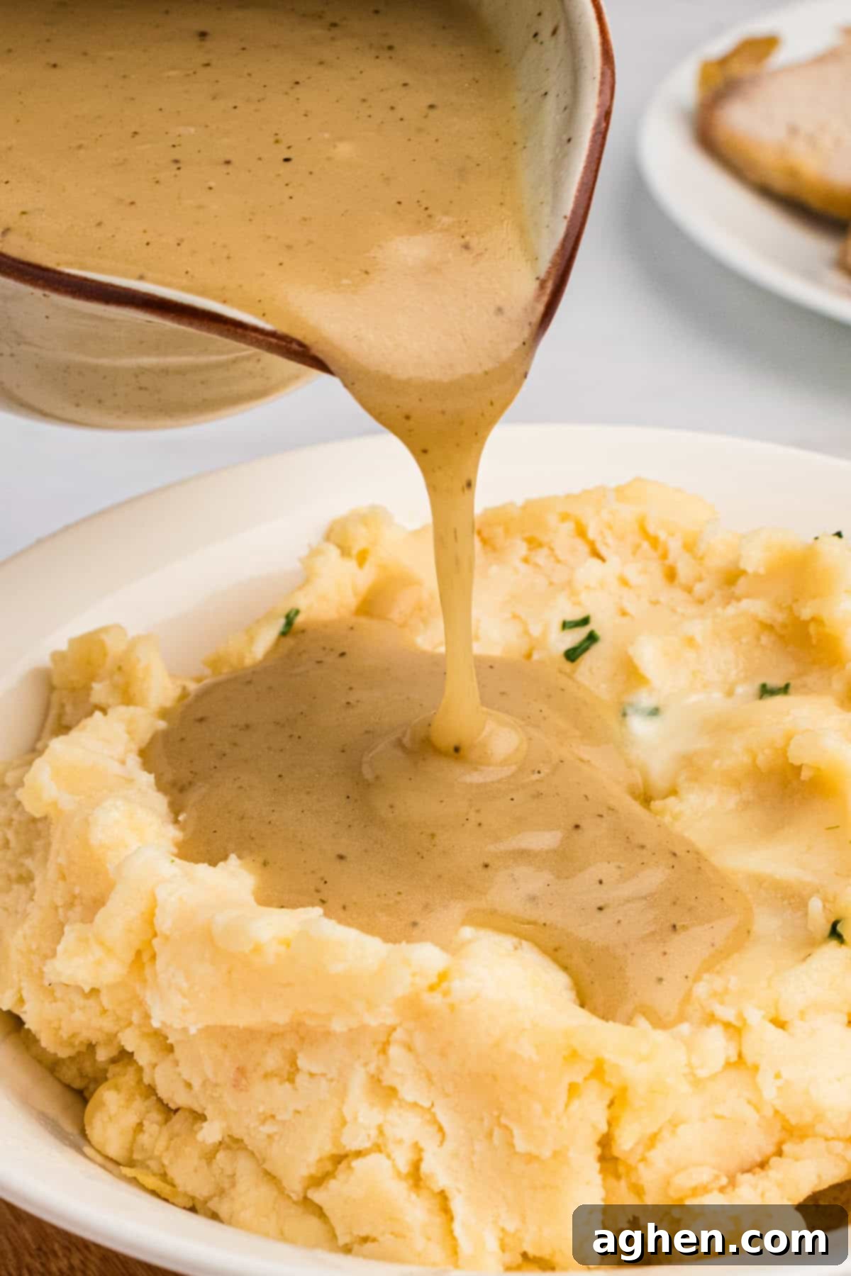 Quick and easy homemade gravy being generously poured over a serving of creamy mashed potatoes, highlighting its appealing texture.