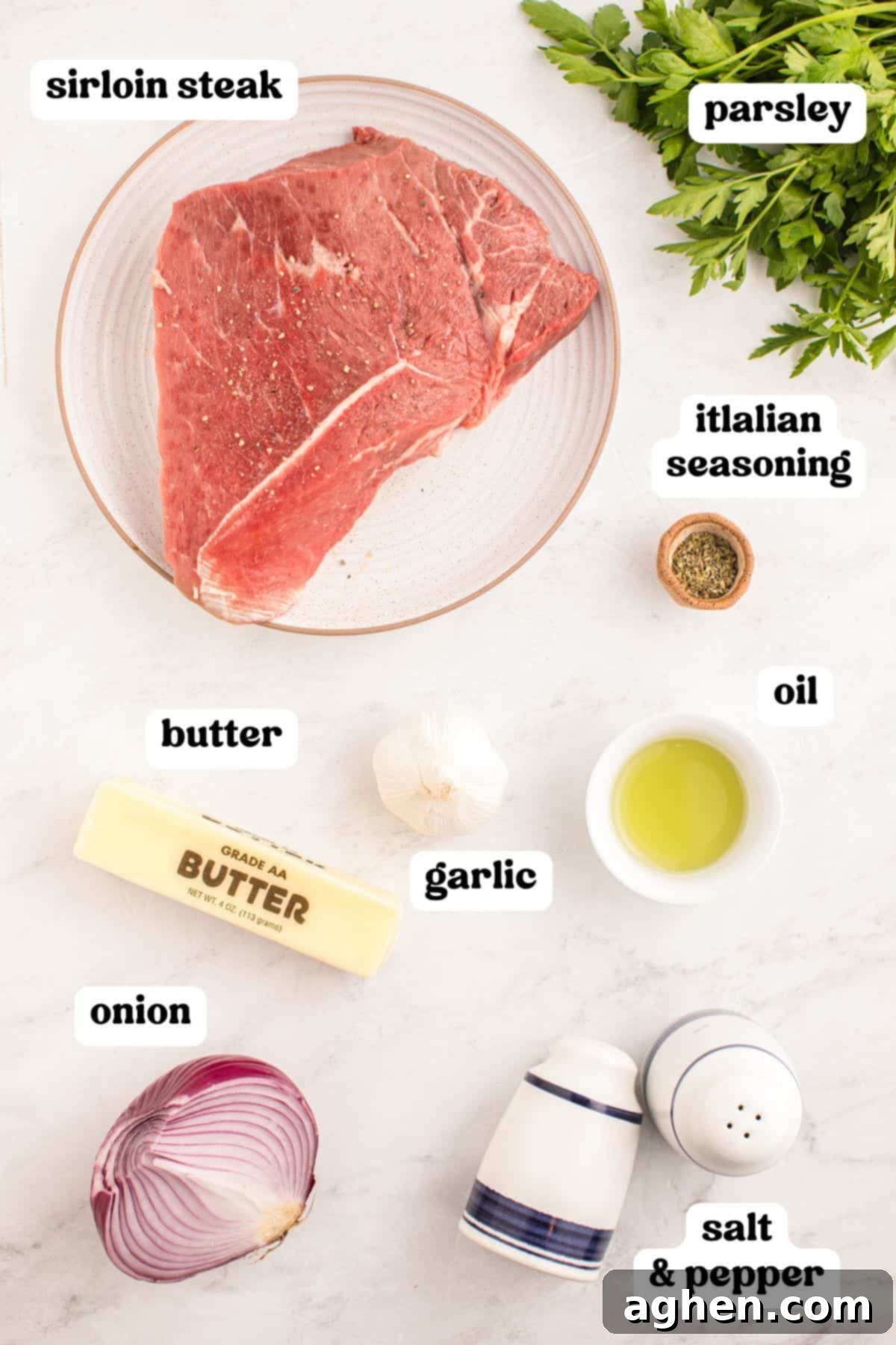 Ingredients for garlic butter steak bites, including raw steak, garlic, butter, parsley, and seasonings laid out on a countertop.