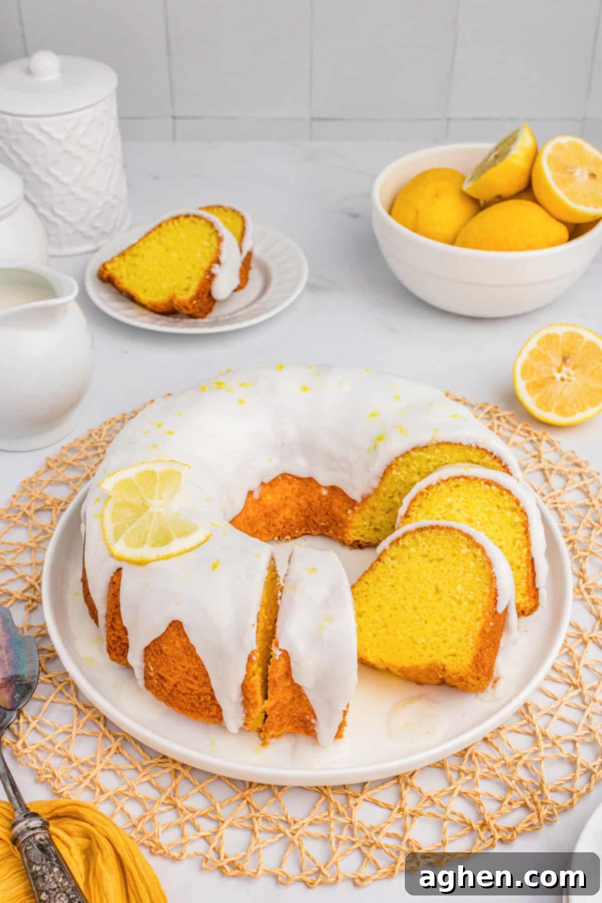 Effortless Lemon Bundt Cake Perfection 3 Moist lemon bundt cake with cake mix and a sweet lemon glaze. Sliced to show its fluffy yellow interior. Fresh lemons artfully placed in the background.