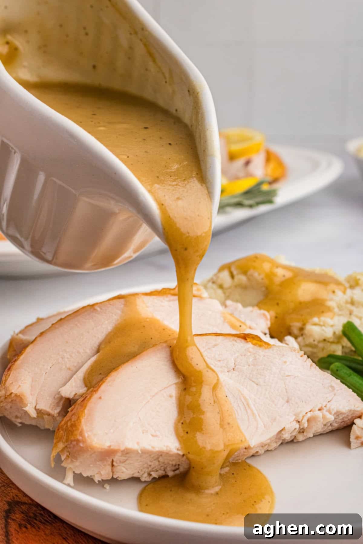 Gravy boat pouring gravy on to slices of roasted turkey.