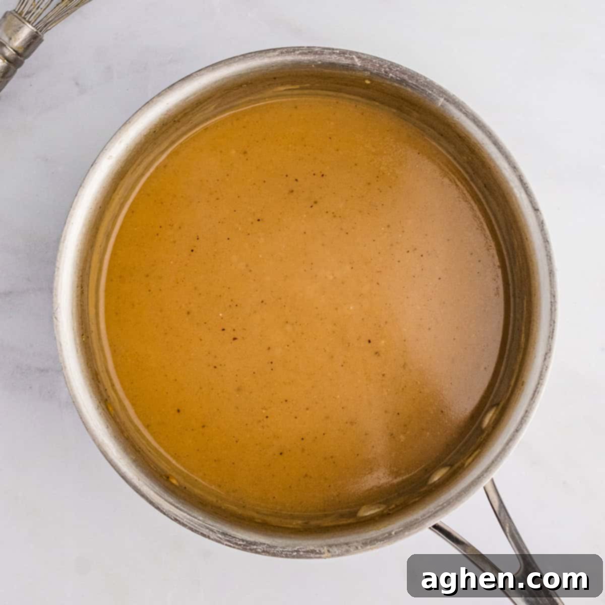Rich, finished turkey neck gravy simmering in a saucepan on the stove, ready to serve.