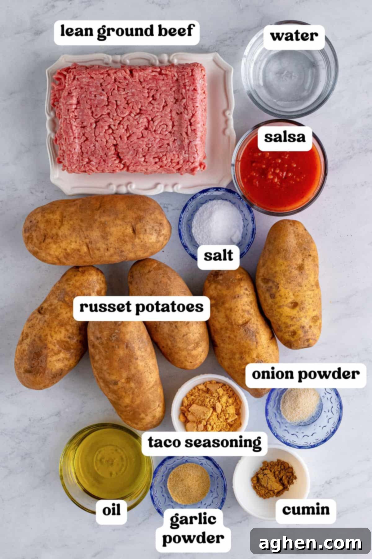 The ingredients for taco stuffed potatoes laid out on a countertop, including russet potatoes, ground beef, olive oil, salsa, and various seasonings.