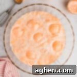 Champagne punch with orange sherbet and pineapple juice in a large glass punch bowl.