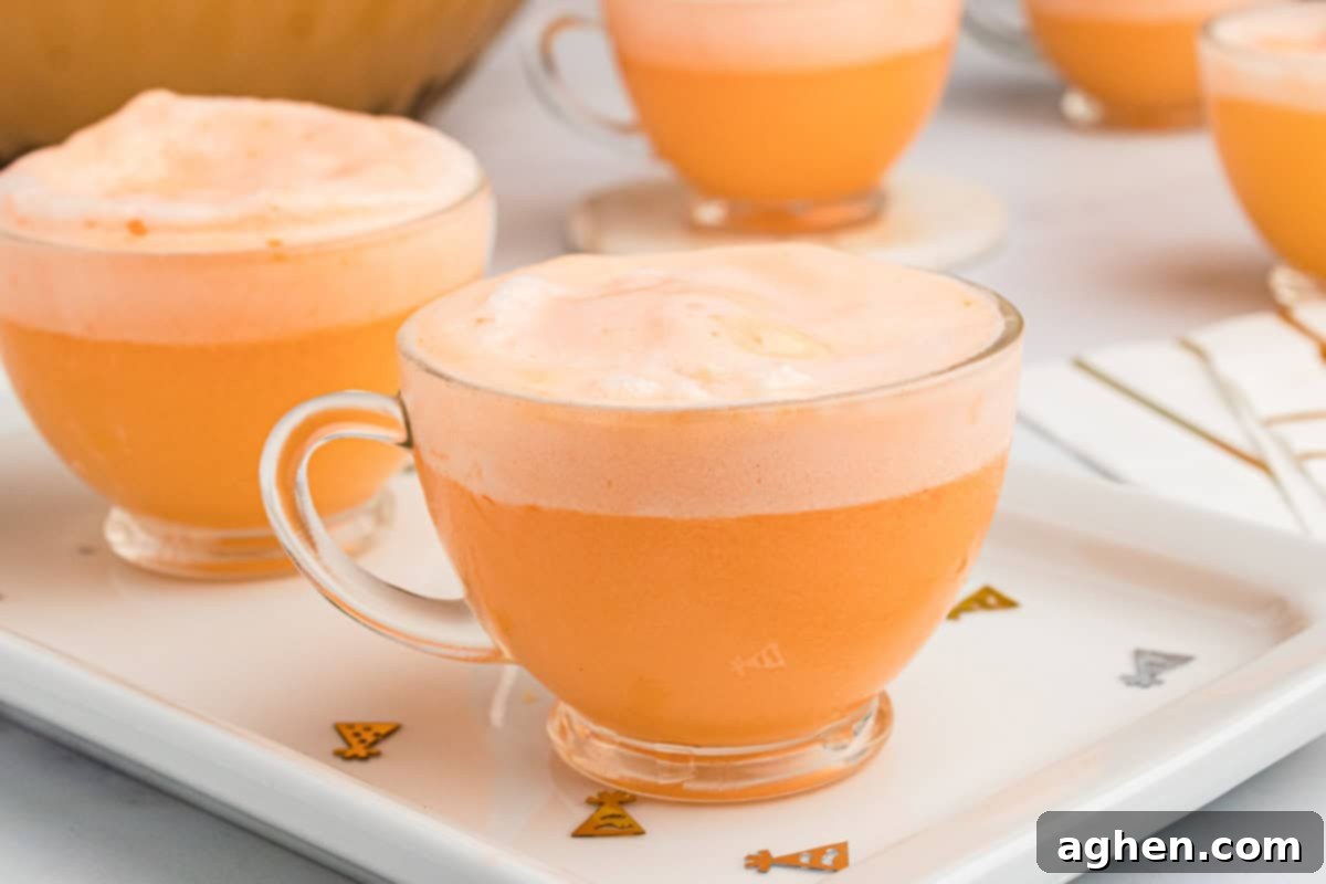 Glass of orange and pineapple champagne punch with orange sherbet melted in and foaming up on top.