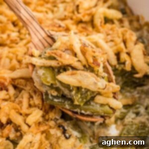 Spoonful of green bean casserole with Worcestershire sauce and crispy fried onions being served with a wooden spoon.