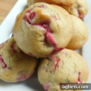 Close-up of a single raspberry lemon muffin with a perfectly golden dome, showing off the raspberries baked into it.