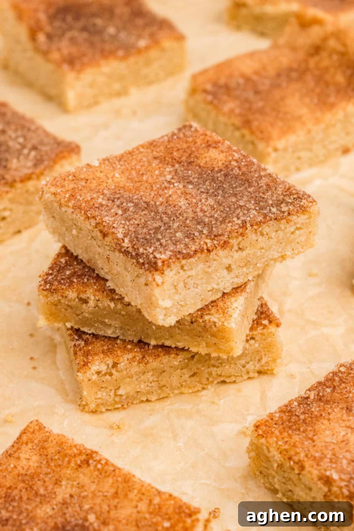Stack of 3 thick bar cookies topped with cinnmamon and sugar on parchment paper.