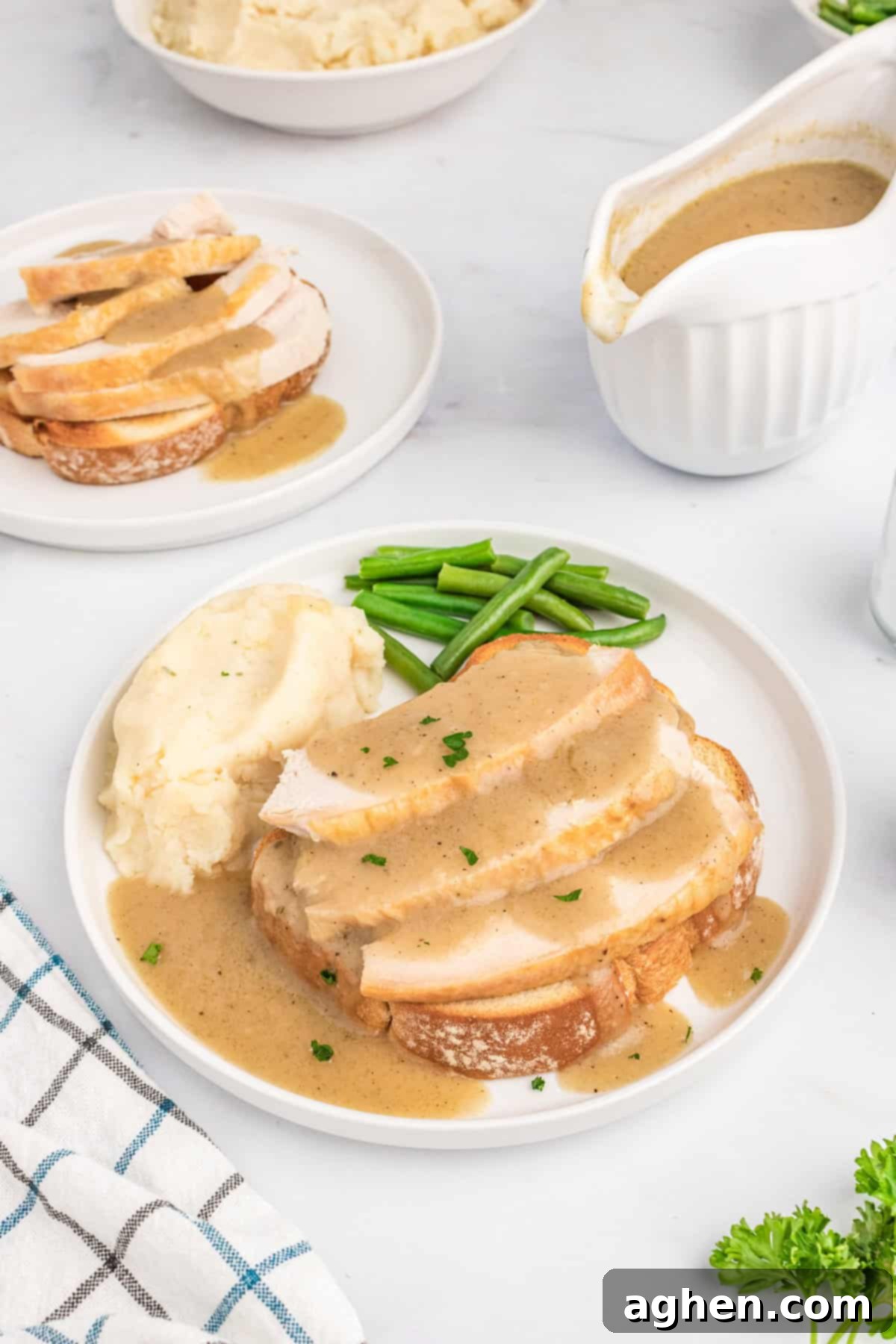 Open Faced Turkey Sandwich 7 Open face turkey sandwich with gravy served with mashed potatoes and green beans. Gravy and another turkey sandwich are in background.