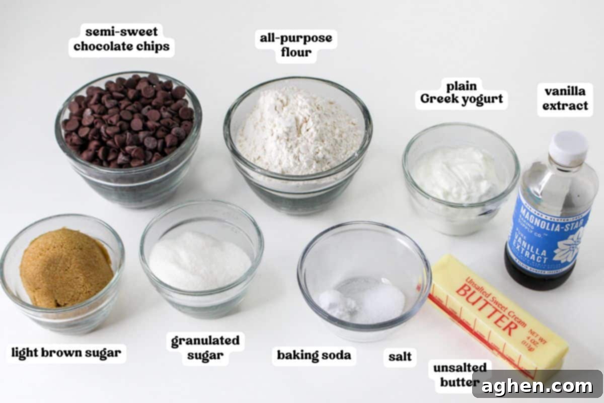 Ingredients for Greek yogurt chocolate chip cookies, including semi-sweet chocolate chips, all-purpose flour, plain Greek yogurt, vanilla extract, light brown sugar, granulated sugar, baking soda, salt, and unsalted butter.