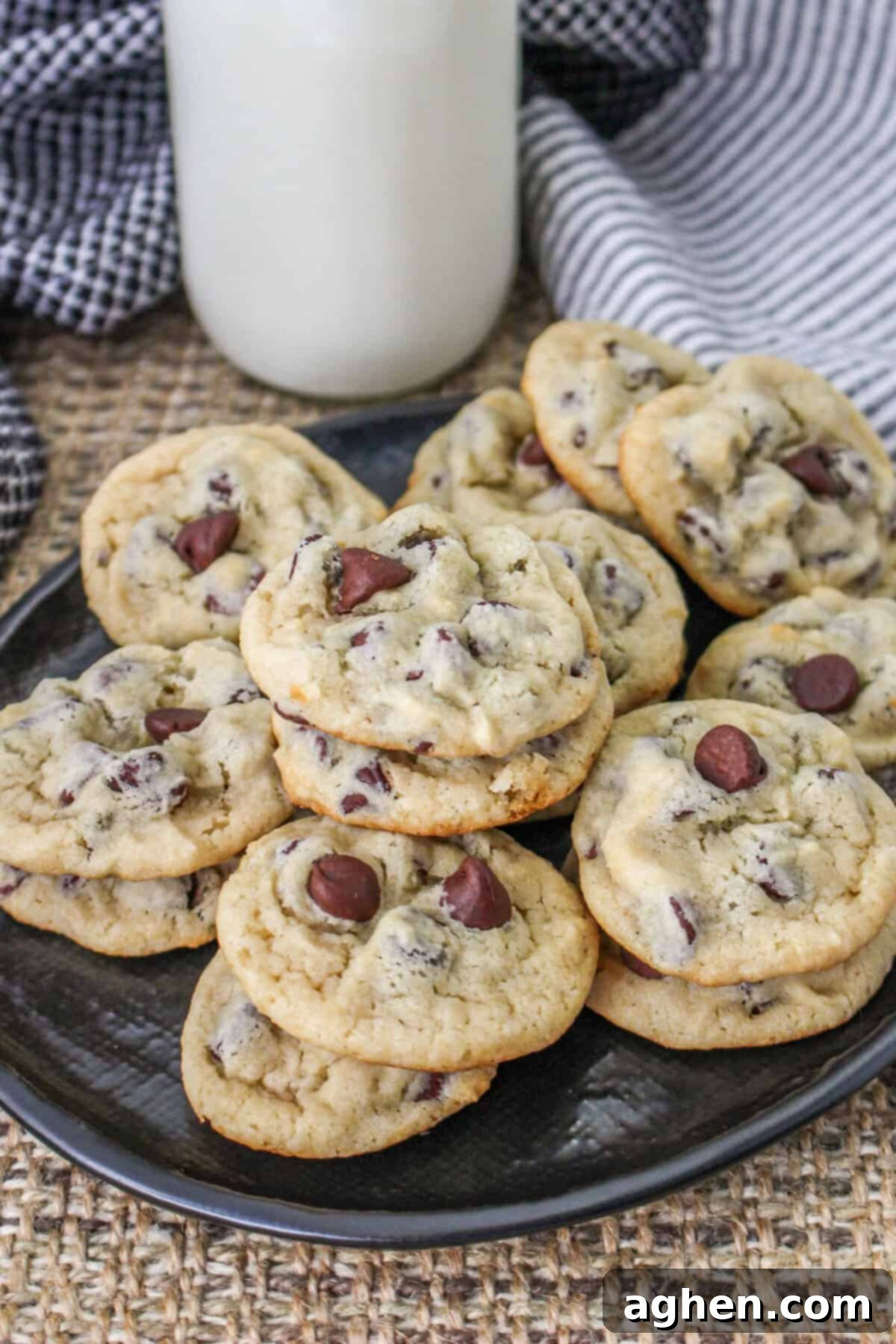 Greek yogurt chocolate chip cookies on a black plate with a glass of milk in background.