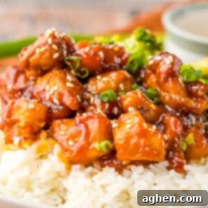 Bourbon chicken like at the mall food court with sesame seeds and green onions over rice, with broccoli in the background.