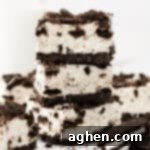 A stack of three Oreo cheesecake bars with crushed Oreo pieces on top. The layers of creamy filling and chocolate cookie crust are clearly visible.
