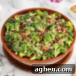 Super Crunchy Broccoli Delight 10 A large wooden bowl filled with broccoli crunch salad, made with fresh broccoli, bacon bits, dried cranberries, shredded carrots, sunflower seeds, and chopped red onions, all lightly coated in a creamy dressing.