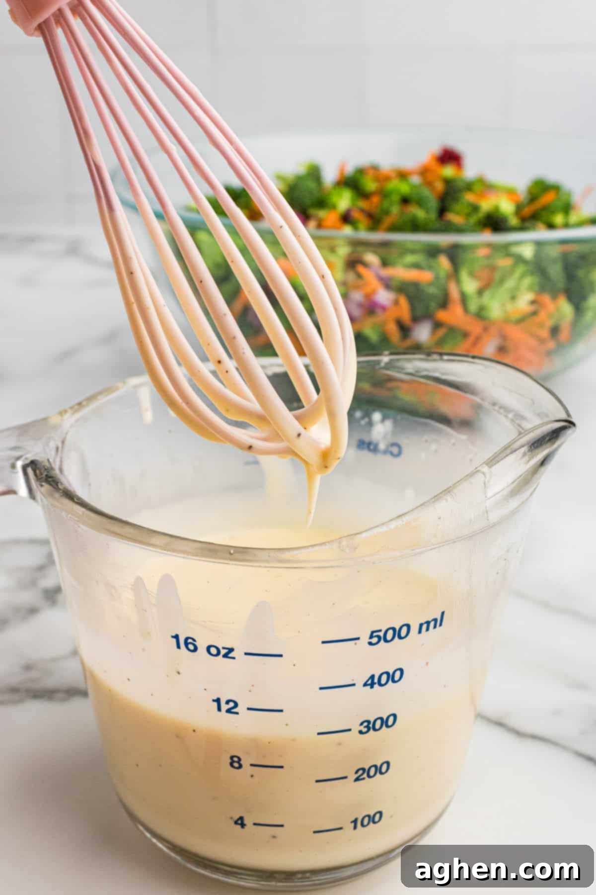 Super Crunchy Broccoli Delight 5 A glass measuring cup of creamy dressing with a whisk.