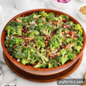 Super Crunchy Broccoli Delight 9 A large wooden bowl filled with broccoli crunch salad, made with fresh broccoli, bacon bits, dried cranberries, shredded carrots, sunflower seeds, and chopped red onions, all lightly coated in a creamy dressing.