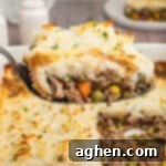 No-Fuss Cottage Pie 11 A close-up shot of a spoonful of cottage pie, highlighting the creamy mashed potato topping and hearty beef and vegetable filling, with the casserole dish in the background.