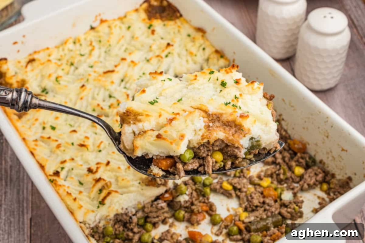 No-Fuss Cottage Pie 9 A serving of cottage pie being lifted from a baking dish, revealing the filling underneath.