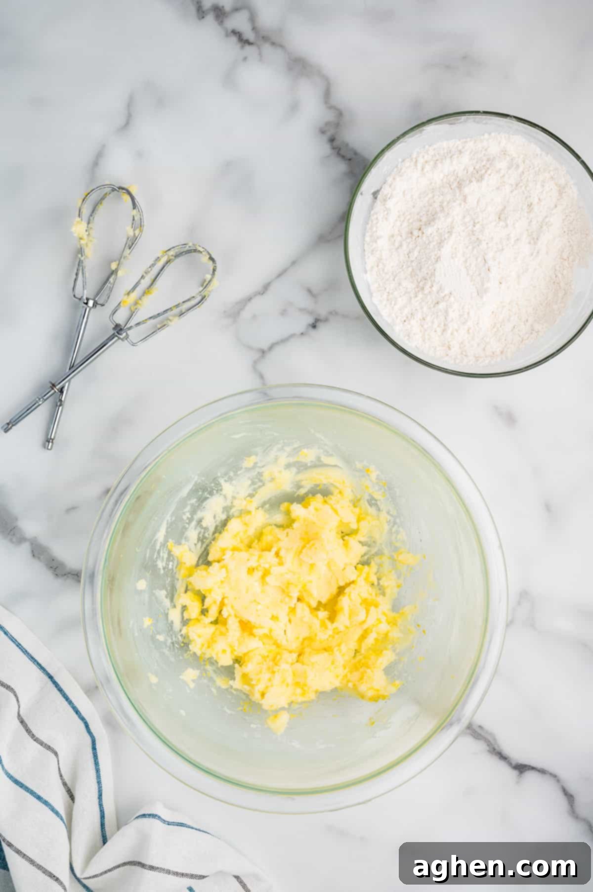 A bowl of creamed butter with a bowl of flour.