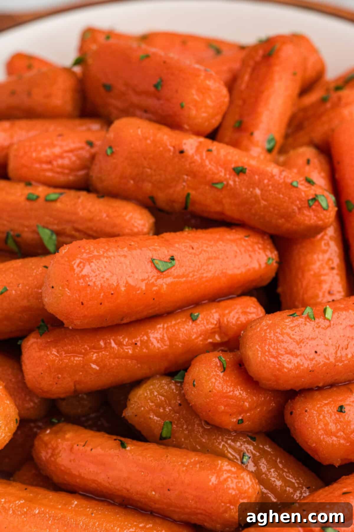 A close-up of brown sugar honey glazed carrots garnished with chopped herbs.