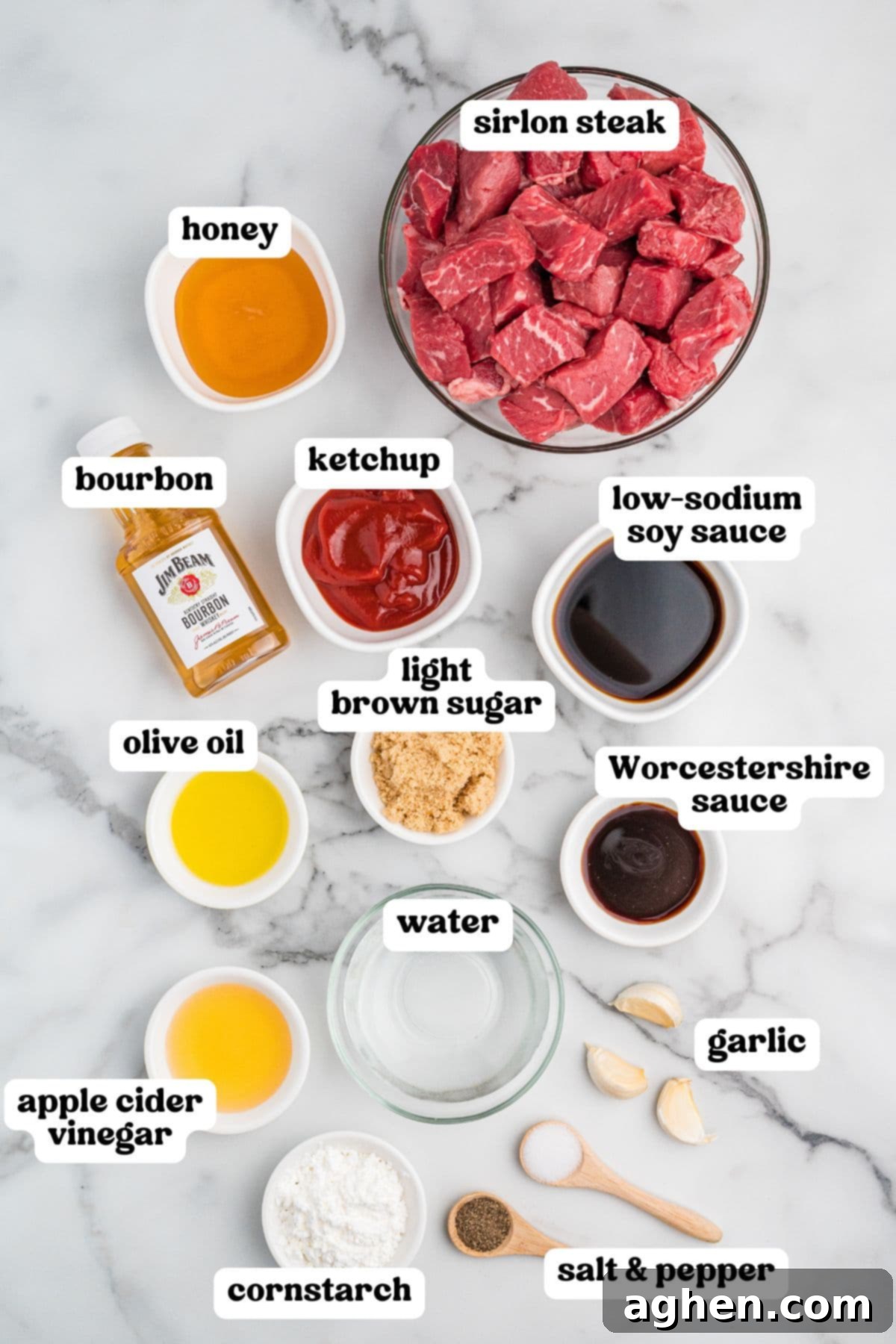 Overhead photo of ingredients, including raw sirloin steak chunks, bourbon, honey, ketchup, low-sodium soy sauce, olive oil, light brown sugar, Worcestershire sauce, apple cider vinegar, water, cornstarch, garlic cloves, and salt and pepper.