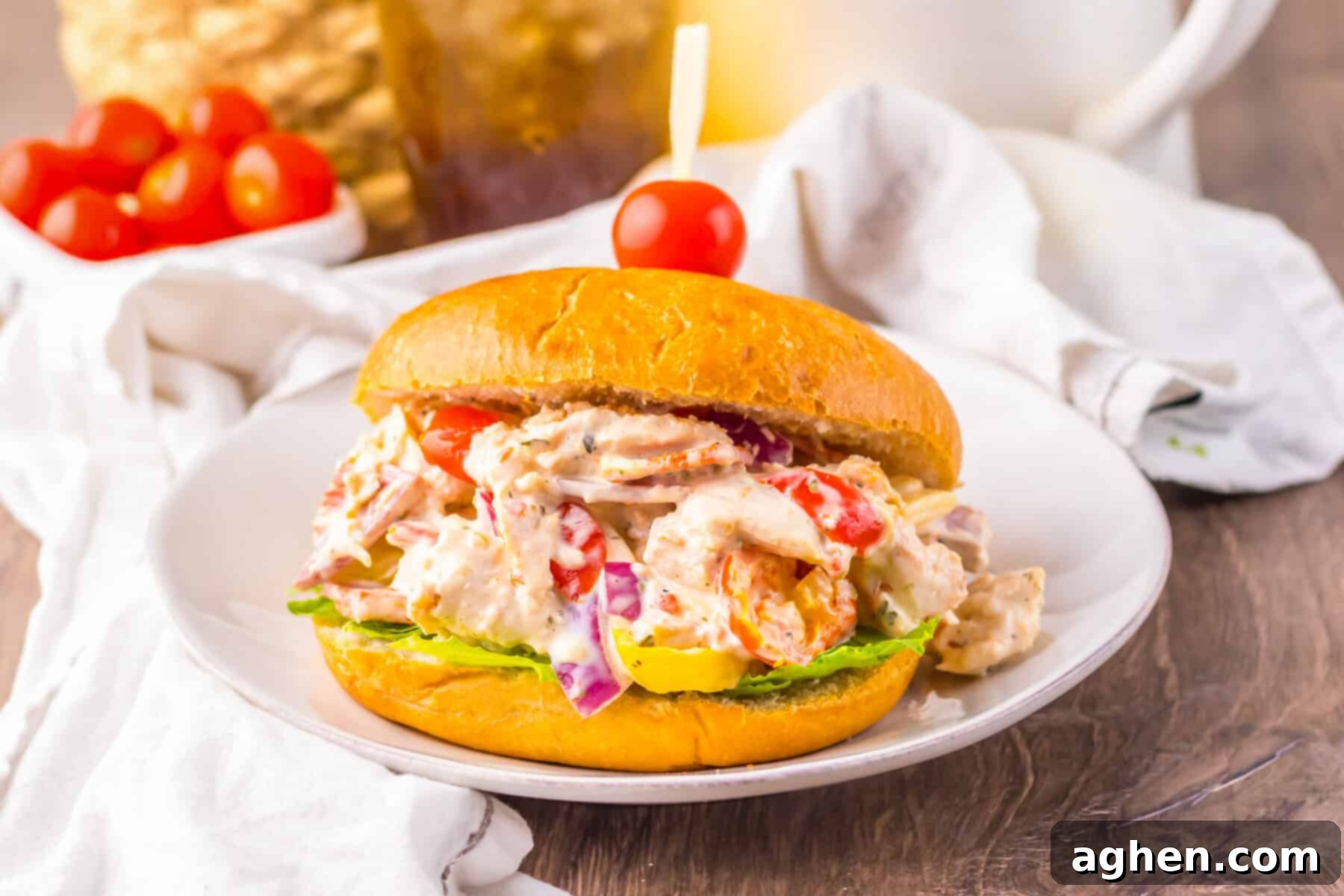 Italian grinder chicken salad sandwich with drink in background.
