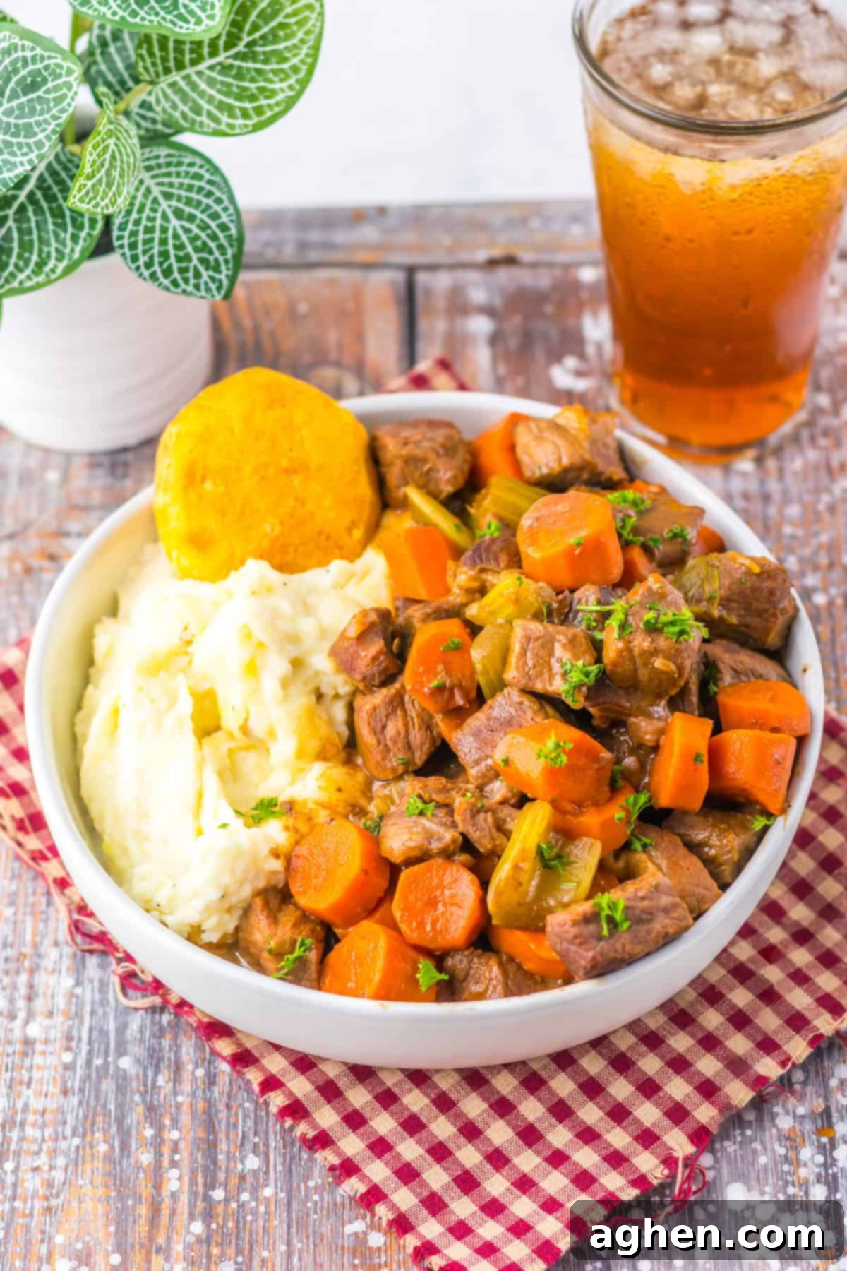 Bowl of slow cooker cracker barrel copycat pot roast with carrots, celery, mashed potatoes, and a biscuit.