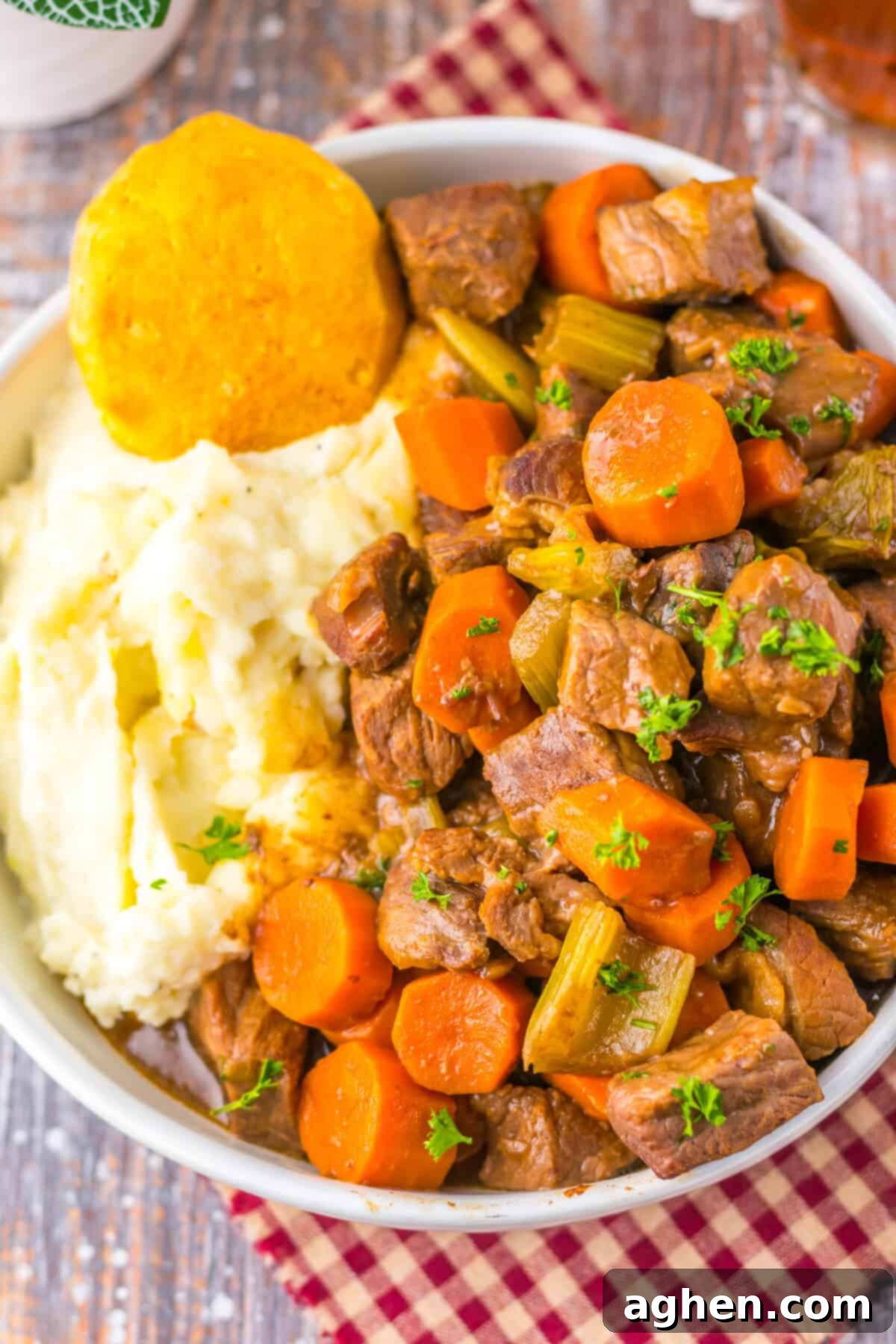 A bowl of hearty copycat Cracker Barrel pot roast with chunks of beef carrots, and celery in rich gravy. Creamy mashed potatoes and a golden biscuit are served on the side.