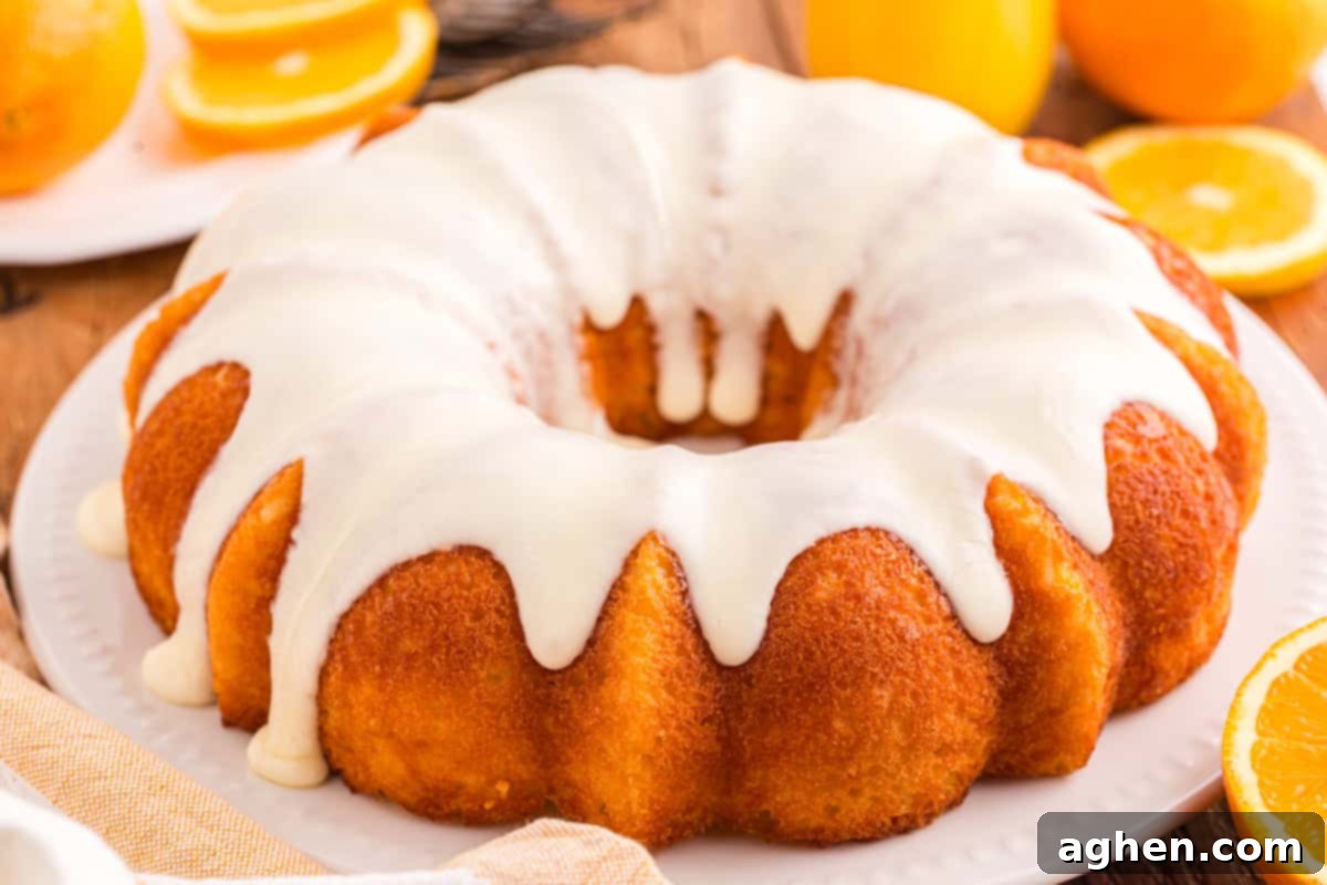An orange bundt cake with white icing on a plate.