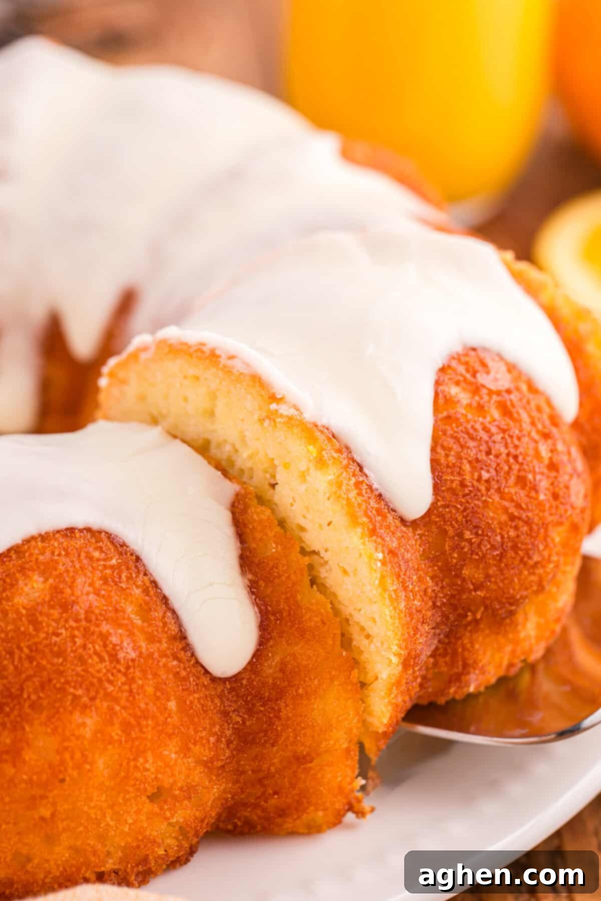 A slice of orange juice cake being lifted from glazed orange bundt cake.
