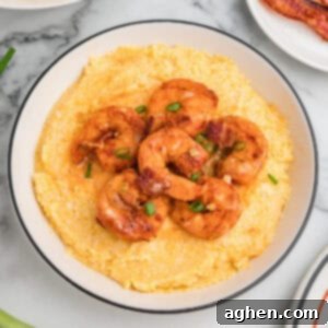 A bowl of cheesy shrimp and grits garnished with green onions and bacon.