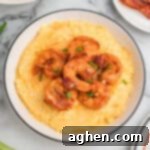 A bowl of cheesy shrimp and grits garnished with green onions and bacon.