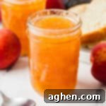 Jars of homemade peach jam with whole peaches, a spoon, and a plate with sliced bread in the background. Homemade Peach Jam - Share your creation!