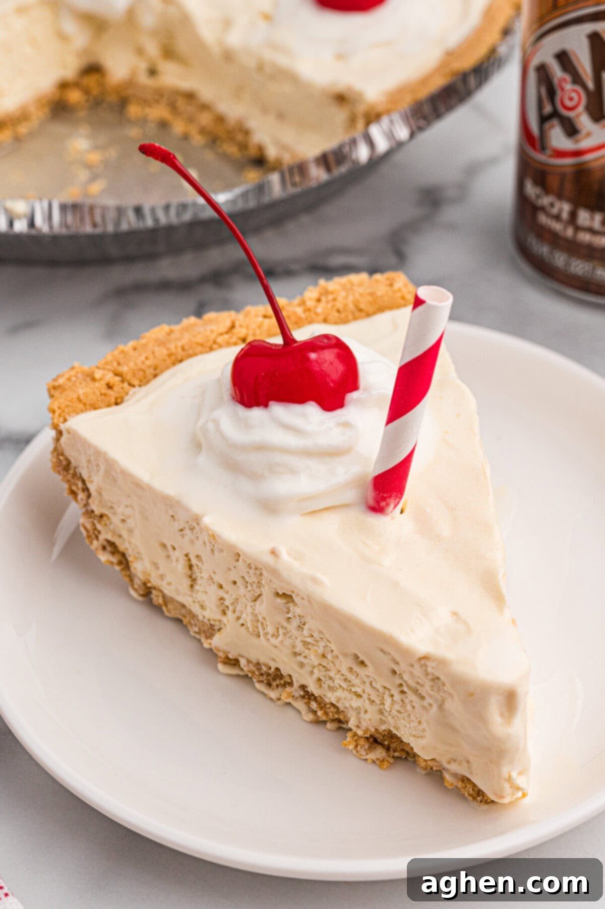 A slice of root beer float pie on a white plate, topped with whipped cream, a cherry, and a red-striped paper straw, showcasing its creamy texture and inviting presentation.