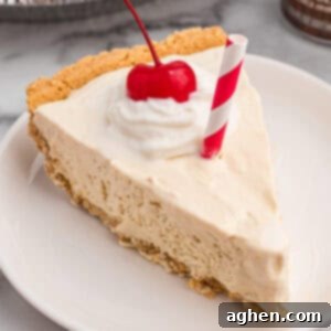 A slice of root beer float pie on a plate, topped with whipped cream, a cherry, and a red-striped paper straw.
