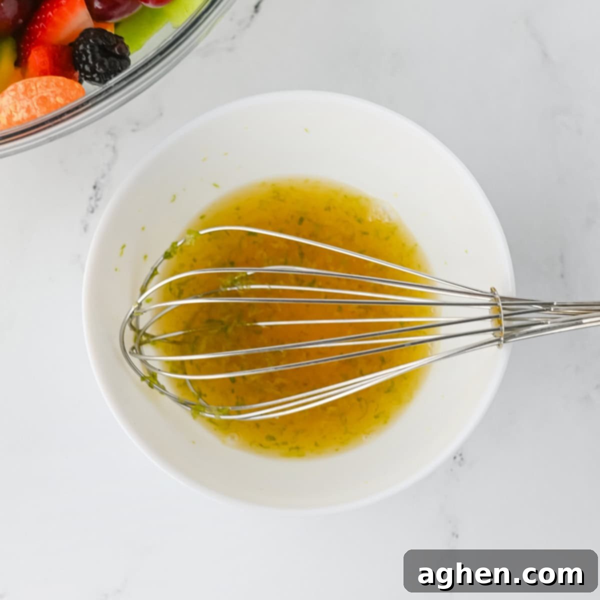 Honey lime dressing in a bowl with a whisk.