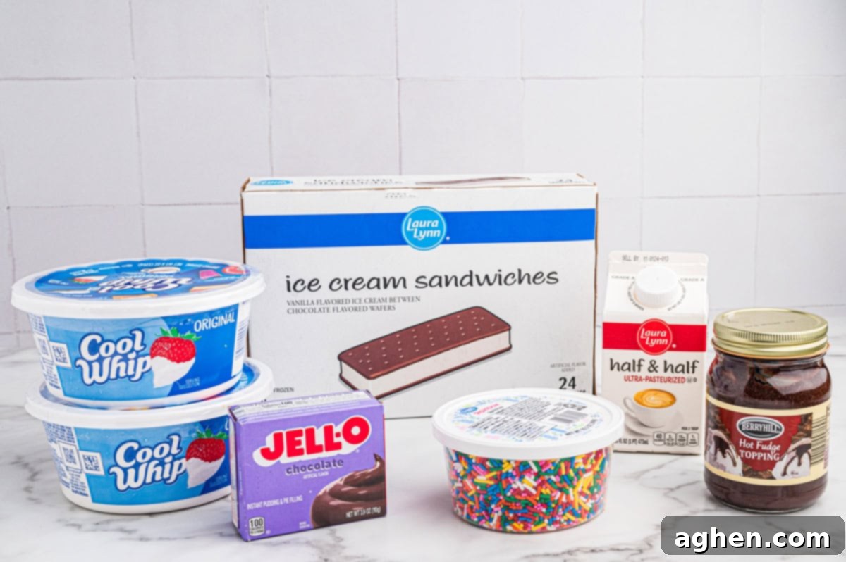 A flat lay photograph showcasing all the ingredients for a homemade ice cream sandwich cake: two tubs of thawed Cool Whip, a box of vanilla ice cream sandwiches, a carton of half & half, a bottle of chocolate fudge topping, rainbow sprinkles, and Jell-O brand instant chocolate pudding mix.