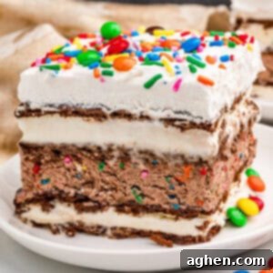 A delicious slice of homemade ice cream sandwich cake, topped with vibrant sprinkles and colorful M&Ms, presented on a plate.