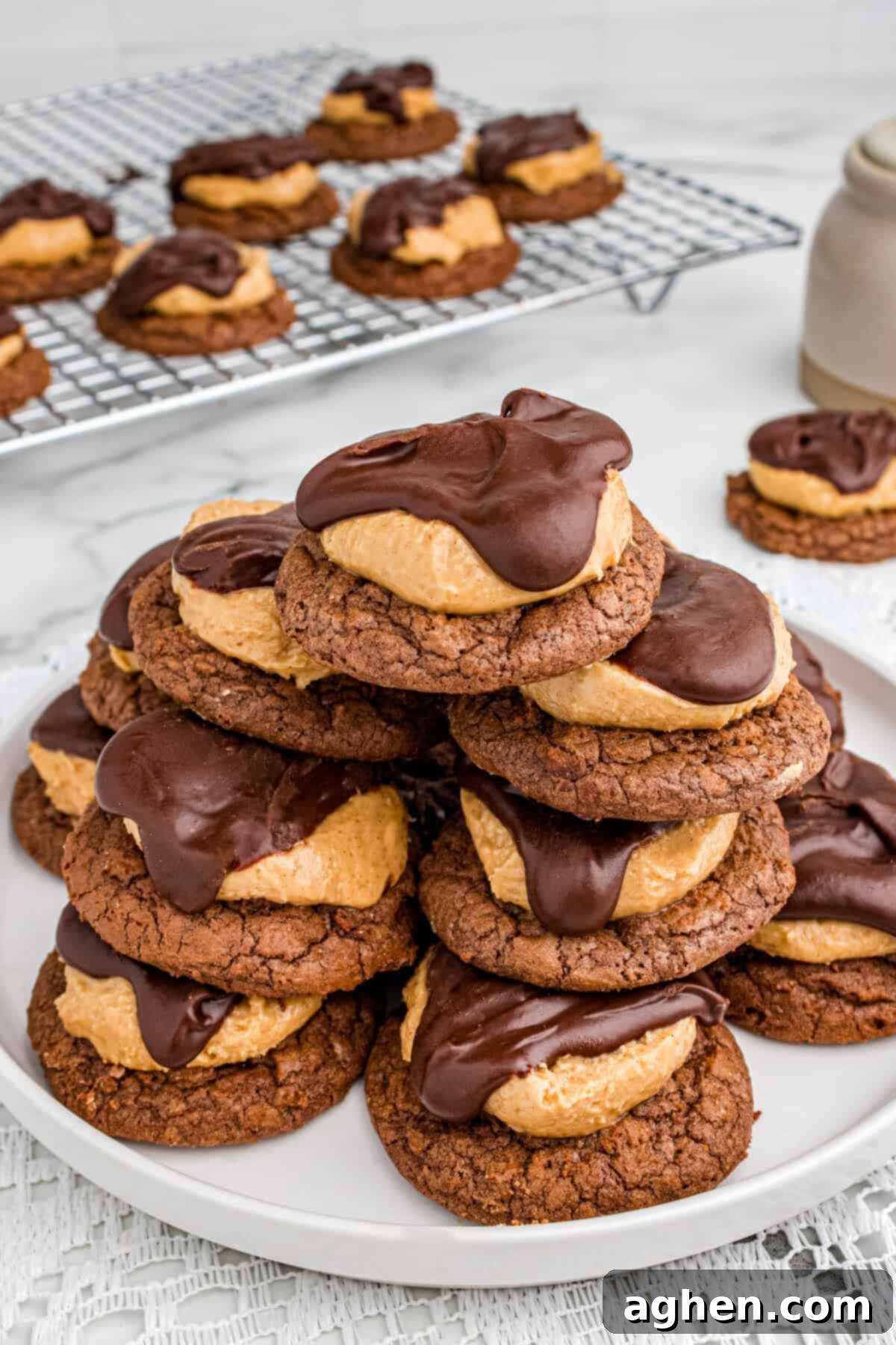 Plate stacked with peanut butter buckeye cookies, chocolate brownie cookies topped with a dollop of creamy peanut butter filling and covered partially with a smooth layer of chocolate ganche.