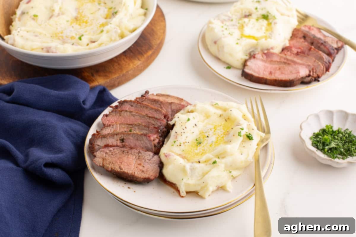 Plate of red skinned mashed potatoes with sliced beef.