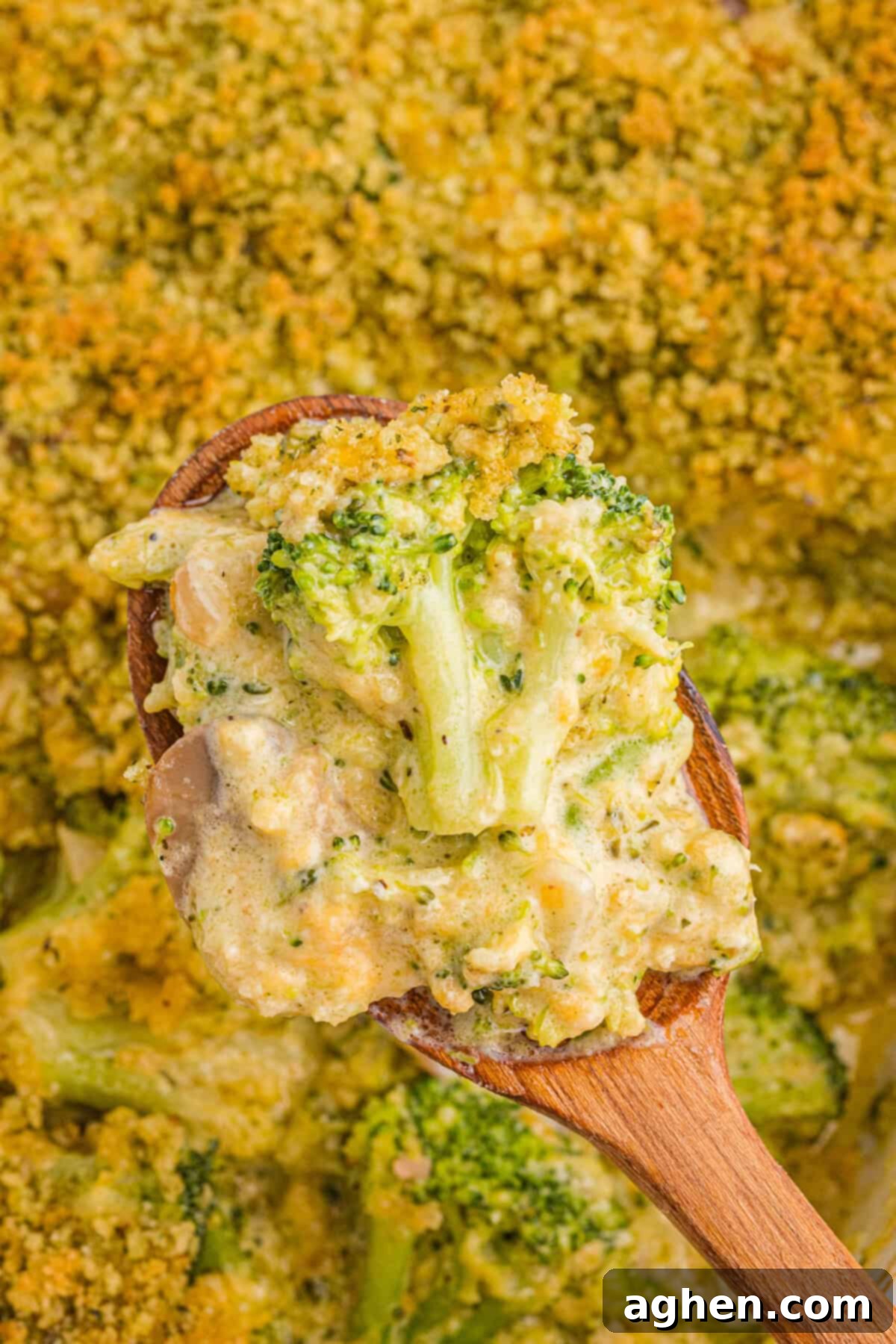 Cheesy Broccoli Delight 9 Close-up of a wooden spoon lifting a portion of broccoli casserole, showing creamy broccoli florets with mushrooms and a crispy golden panko breadcrumb topping.