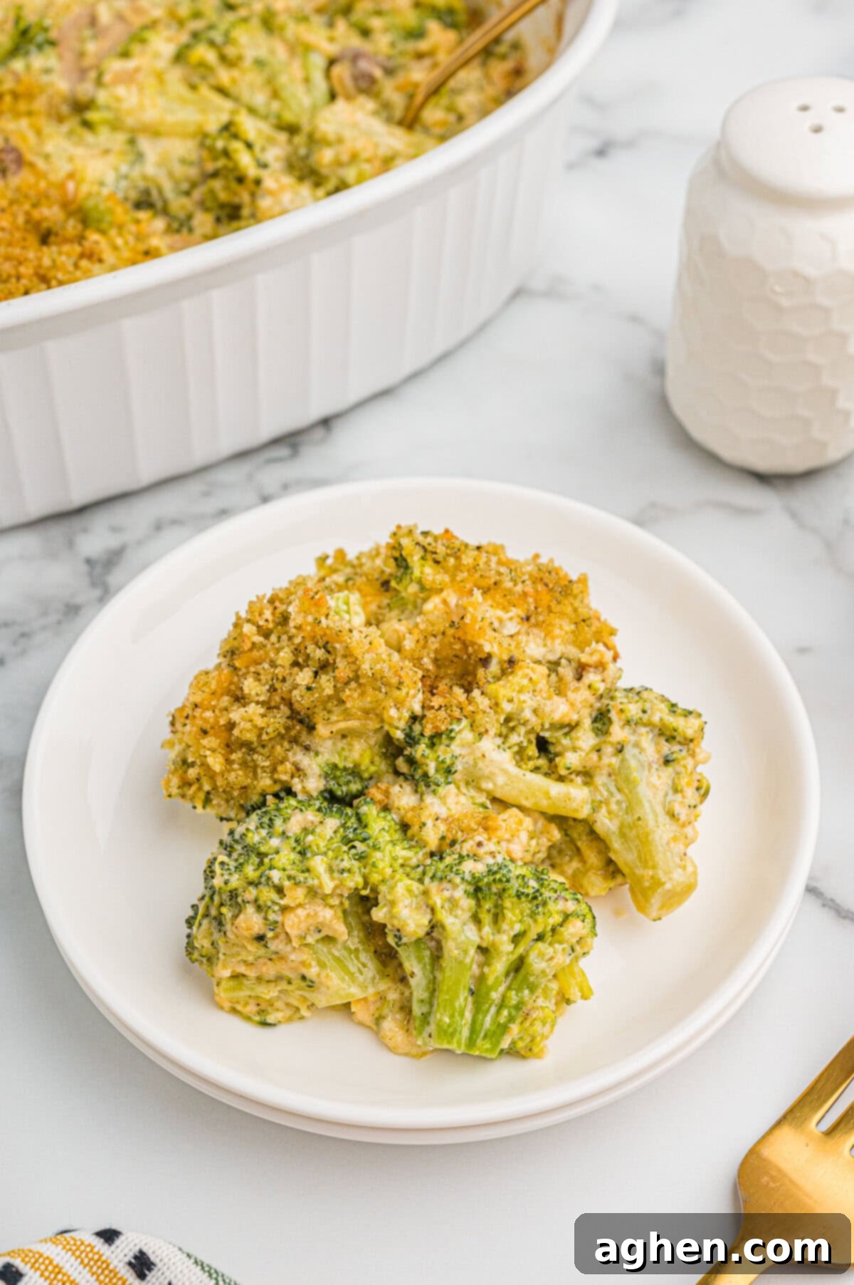 Cheesy Broccoli Delight 10 Serving of broccoli cheese casserole on a white plate.