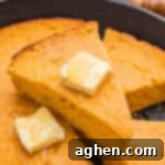 Slice of moist sweet potato cornbread with honey butter on a plate.