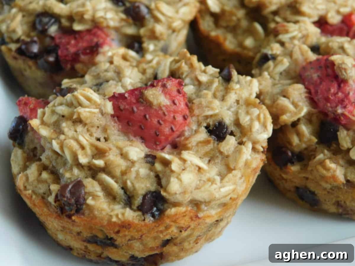 Strawberry oatmeal muffins cooling on a tray with a dusting of powdered sugar