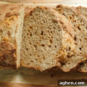 A warm, golden brown slice of Snickerdoodle Butterscotch Bread, garnished with a sprinkle of cinnamon sugar, sits enticingly on a cooling rack, ready to be devoured. The rich butterscotch chips peek out from the soft, moist crumb.