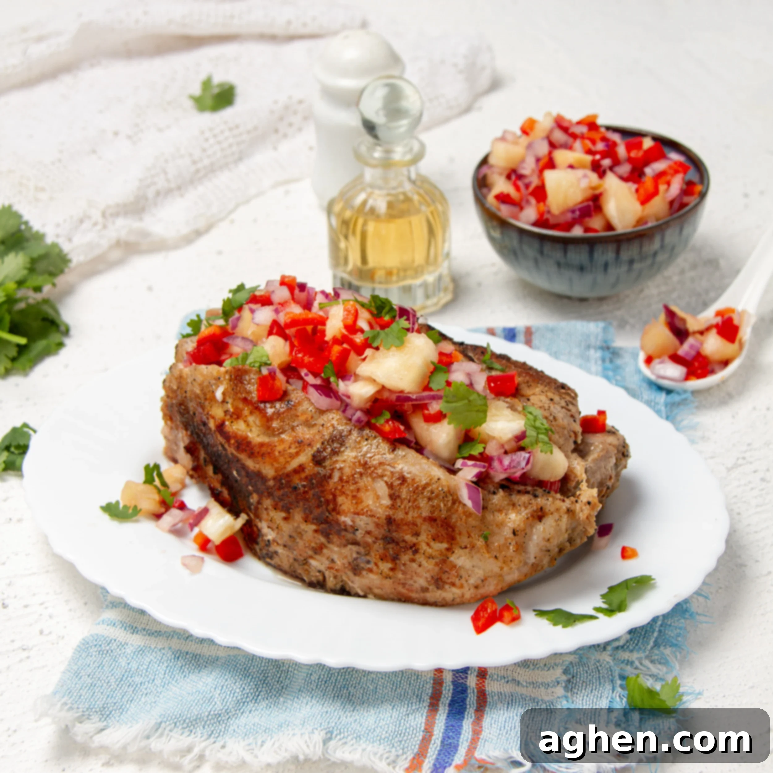 Pineapple Salsa Pork Tenderloin Feast 2 Tropical and delicious pork tenderloin with pineapple salsa on a plate with extra salsa and oil on the side.