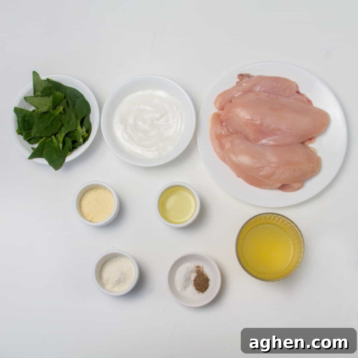 Luscious Light Chicken Florentine 3 Raw chicken breast, plain low-fat yogurt, fresh spinach, olive oil, grated parmesan cheese, cornstarch, salt, and black pepper displayed in individual bowls.