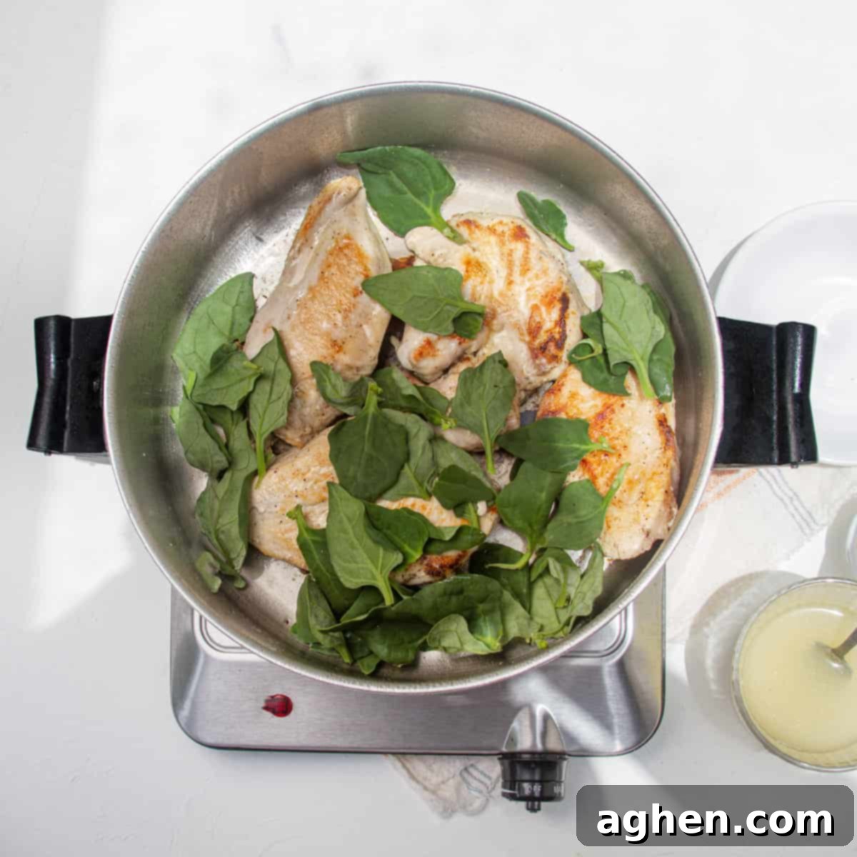 Luscious Light Chicken Florentine 5 Chicken and spinach cooking in a hot pan, spinach wilting around the chicken.