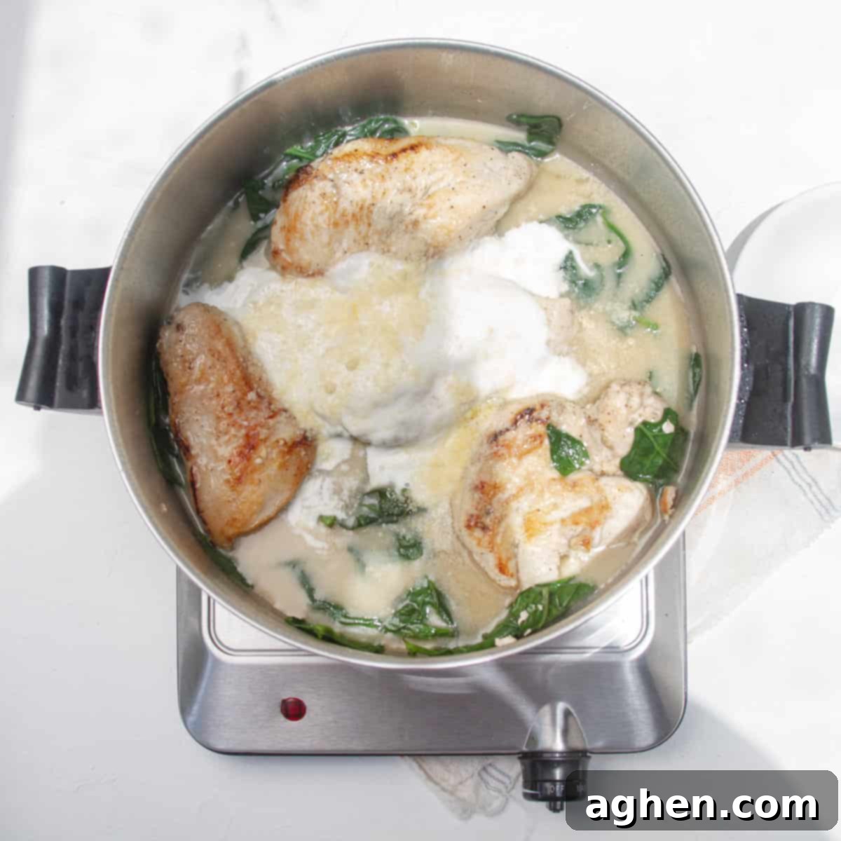 Luscious Light Chicken Florentine 6 Chicken and spinach simmering in a creamy sauce in a pan.